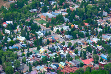 Telluride, Colorado, aerial photo showing the rooftops of houses and green trees in the colorful neighborhoods of this box canyon town in the Rocky Mountains on a summer morning. - 536215710