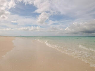 Fototapeta premium Beautiful sunny day on a calm pristine beach with grey skies in Indonesia