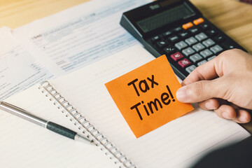 Time for Taxes Money Financial Accounting Taxation Concept.Hand holding a paper with tax time text on tax forms. Assistance with filing tax forms and calculations.Financial research.