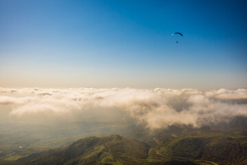 北海道のニセコ上空で雲より高い所を飛ぶパラグライダーを空撮