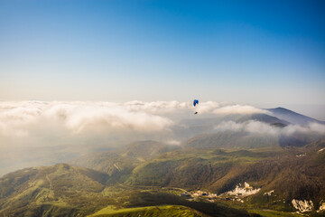 北海道のニセコ上空で曇りよ高く飛ぶパラグライダーを空撮
