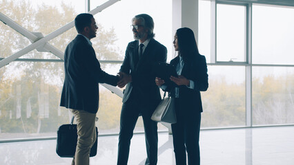 Business people multi-ethnic group are meeting in new office center shaking hands discussing property rent looking around and talking