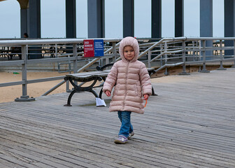 gregarious young girl is playing at the boardwalk in winter near Coney Island Park