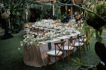 a beautiful wedding decoration arrangement. Table settings. Table Decoration for intimate private party outdoors with fairy light and white flowers. 