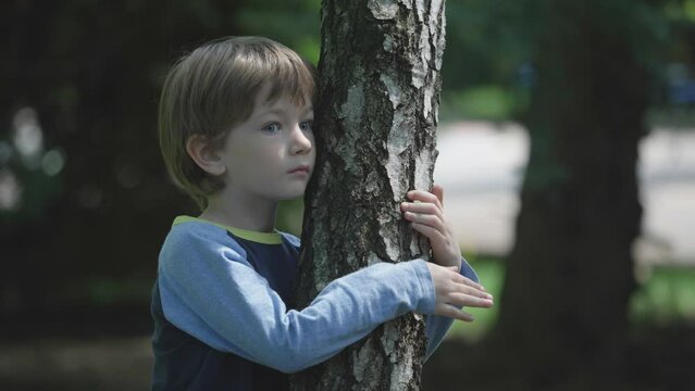 Pretty boy hugs the tree in the forest, environment protection concept