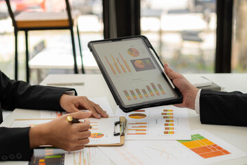 Businessman analyzing financial statistics displayed on a tablet screen. Business colleagues working and analyzing financial numbers on digital tablets.