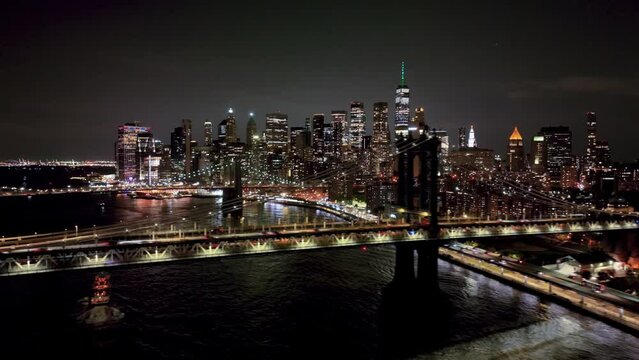 aerial view of cars driving across over Manhattan Bridge and Brooklyn Bridges on East River with Freedom Tower and skyline bright lights in New York City at night in NYC