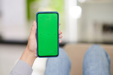 Hand of young woman holding smartphone with black green screen