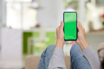 Smartphone with blank green screen held by young woman in casualwear