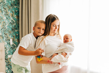 Lifestyle family portrait of parents with newborn baby child and older son. Happiness and love at home indoors
