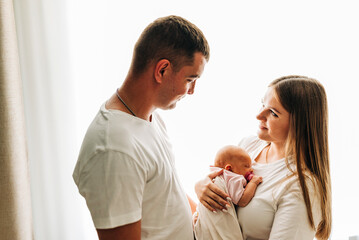 Lifestyle family portrait of parents with newborn baby child. Happiness and love at home indoors