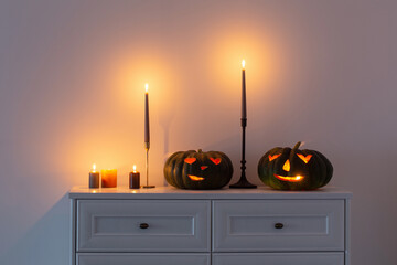 black halloween pumpkin with burning candles in white interior
