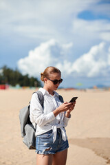 Tourist using mobile phone on the beach