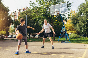Obraz premium Father and his son enjoying together on basketball court.