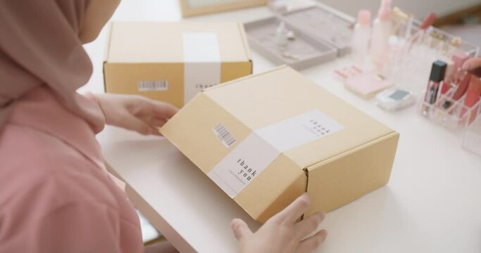 Islam asia people young adult woman prepare wrap gift post parcel carton box on office desk. Closeup hand small SME shop store owner sell online send product by postal supply chain service solution.