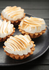 Appetizing lemon cupcakes with white cream on dark plate. Holiday, surprise, birthday, Valentine's Day. Vertical photo.