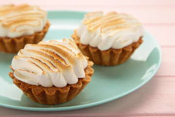 Appetizing lemon cupcakes with white cream on blue plate on pink wooden background. Holiday, surprise, birthday, Valentine's Day.