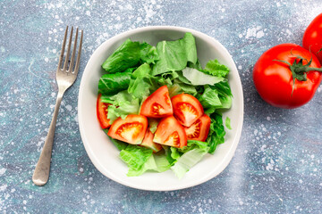 Healthy food tomato vegetable salad in bowl on blue wood background.