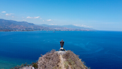 Popular landmark of Cristo Rei statue overlooking blue ocean and capital city of Dili, Timor Leste, South East Asia, aerial drone view of landscape and ocean