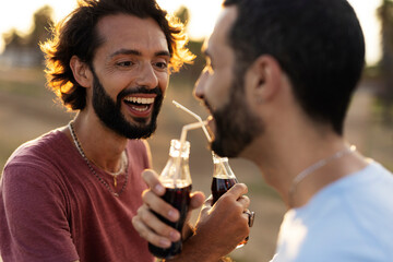 Gay couple embracing and showing their love. Young men drinking juice.