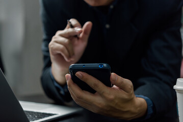 Man hand holding mobile smartphone digital technology network communications at desk.