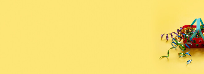 Shopping basket with spirals of tinsel and bag on top on a colored background. Copy space.