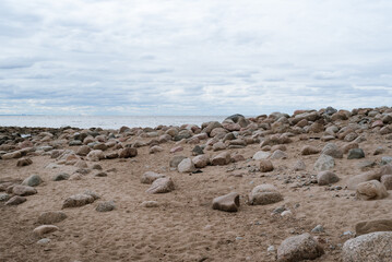 Sandy beach with stones on a cloudy day. Idea for an interior poster. Copy space