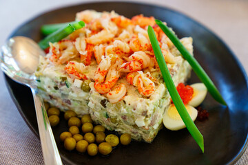 portion salad with shrimp, quail eggs, caviar and canned peas in a plate.