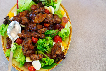 salad with caramelized eggplant, tomatoes, quail eggs and lettuce on a plate.
