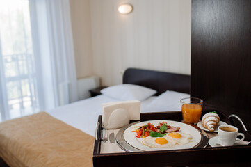 Fototapeta na wymiar Tasty fresh breakfast with scrambled eggs and vegetables in bed at the hotel room