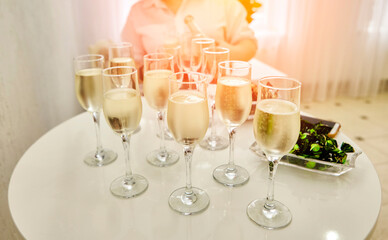The waitress distributes sparkling white wine to the guests.