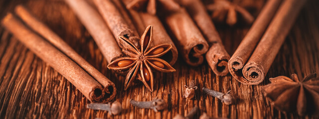 Christmas spices closeup. Star anise, cinnamon sticks, cloves on an old dark wooden table. Selective focus. Side view. Banner - Powered by Adobe