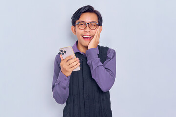 Cheerful young Asian man in casual shirt holding mobile phone and touching her cheek, looking at camera isolated on white background