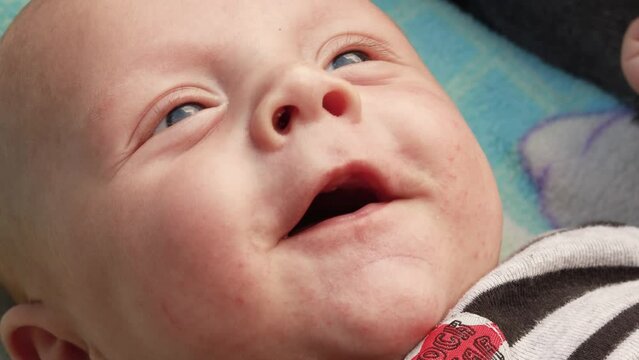 4k footage video. Close up newborn baby child lying in baby carriage stroller buggy having fun playing, looking at her mother, smiling infant. Outside walking in pushchair, fresh air

