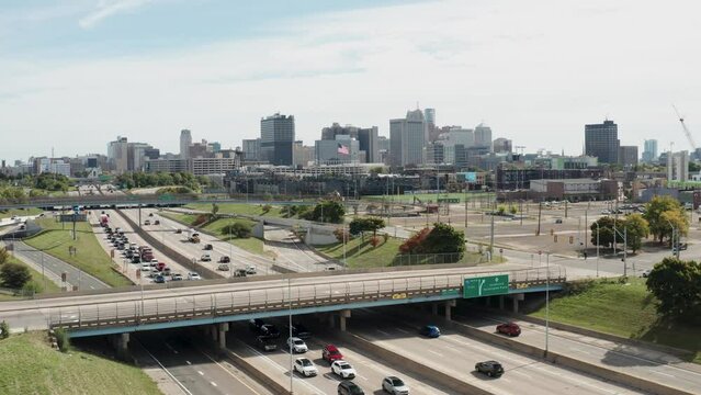 Detroit, Michigan skyline in the background with traffic on Fisher Freeway as drone video moves in.