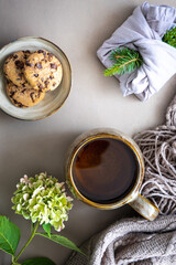 Eine Tasse Tee, Schokoladenkekse auf einem Teller und Blumen auf einem rustikalen Tisch. Draufsicht.