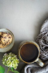 Eine Tasse Tee, Schkolade Kekse auf einem Teller und Blumen auf einem grauen Tisch. Draufsicht, Herbst.