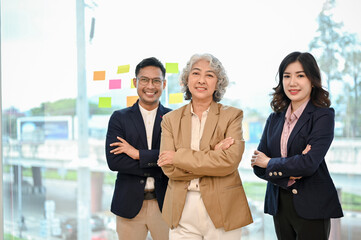 Successful Asian businesspeople in formal suits crossed arms, standing in the office