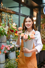 Beautiful attractive young Asian female florist holding a beautiful roses vase