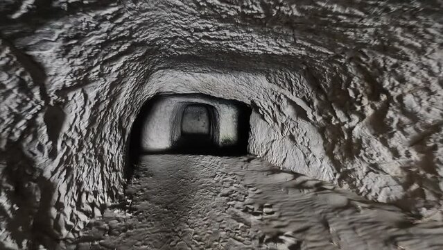 POV: Someone is walking through a dark tunnel with irregular stones on the edge