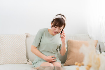 陣痛がきて電話するアジア人女性（妊婦・出産・マタニティ）

