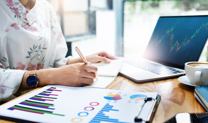 young asian businesswoman sitting on desk office analyze her plan on note book, use paperwork of investment working with computer laptop, Close up view