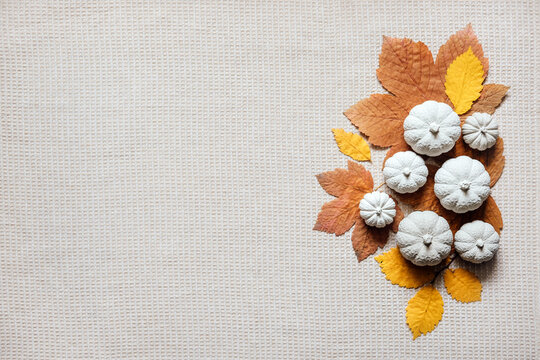 Autumn creative craft background with decorative clay pumpkins and wooden autumn leaves. Decorative pumpkins flat lay on natural fabric background