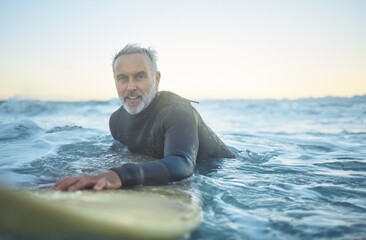 Senior man, surfing in the ocean of Indonesia and free to travel the world in retirement life....