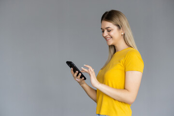 Young woman smiling while using phone isolated over white background