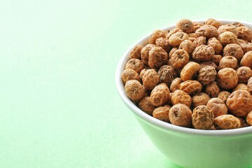 Chufa, tigernut, earth almond on ceramic bowl on green background. Healthy organic food concept. Tiger nut for flour, milk, traditional typical homemade cold fresh drink horchata from Valencia Spain