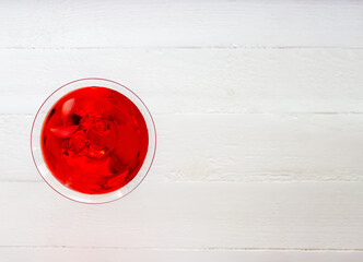Top view of red alcohol cocktail with ice on the white wood table.