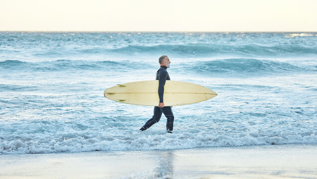 Surf, waves and surfer man walking on a beach with a board for exercise and water fitness. Training, workout and sports activity of a sport athlete ready for cardio and nature exercising outdoor