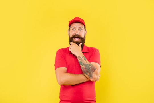 Surprised Bearded Man In Casual Red Cap And Tshirt Stroking Chin Yellow Background, Salesman