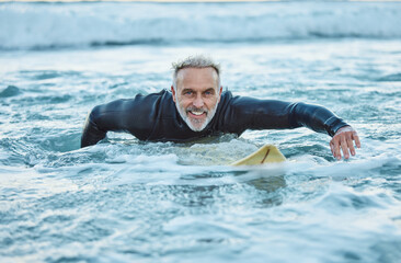 Senior man, water and sports surfer on a beach with smile training for fitness and health or hobby in the outdoors. Elderly male paddling on surfboard for healthy exercise in the ocean waves at sea - obrazy, fototapety, plakaty
